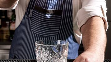 A person holding a clear ice cube over a glass.