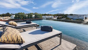 A rooftop pool area with lounge chairs and a clear view of the surrounding buildings. - Vitória Stone Hotel (Évora)
