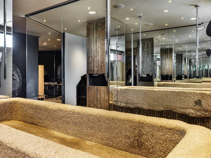 A modern bathroom with multiple sinks, large mirrors, and a stone-textured floor.