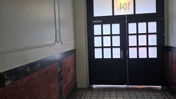 A hallway with a patterned floor, a black door with a sign above it, and a decorative wall.
