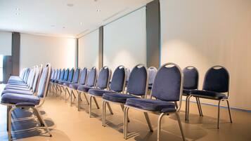 A row of blue chairs with metal frames in a room with a plain wall and a light-colored floor.