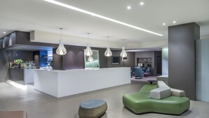 A modern lobby with a reception desk, seating area, and a bar.