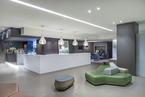 A modern lobby with a reception desk, seating area, and a bar.
