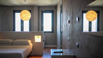 Un dormitorio moderno con cama, mesita de noche y un espejo grande. Hay dos ventanas con cortinas y una lámpara colgante sobre la cama.