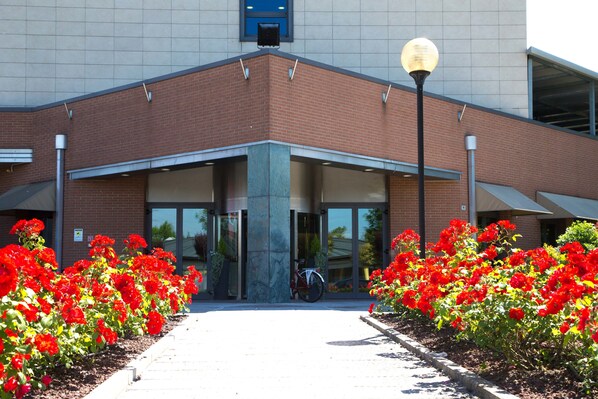 A building entrance with a brick facade, large windows, and a bicycle parked in front.