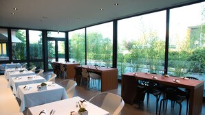 A restaurant with multiple tables, each set with cutlery and a small plant.
