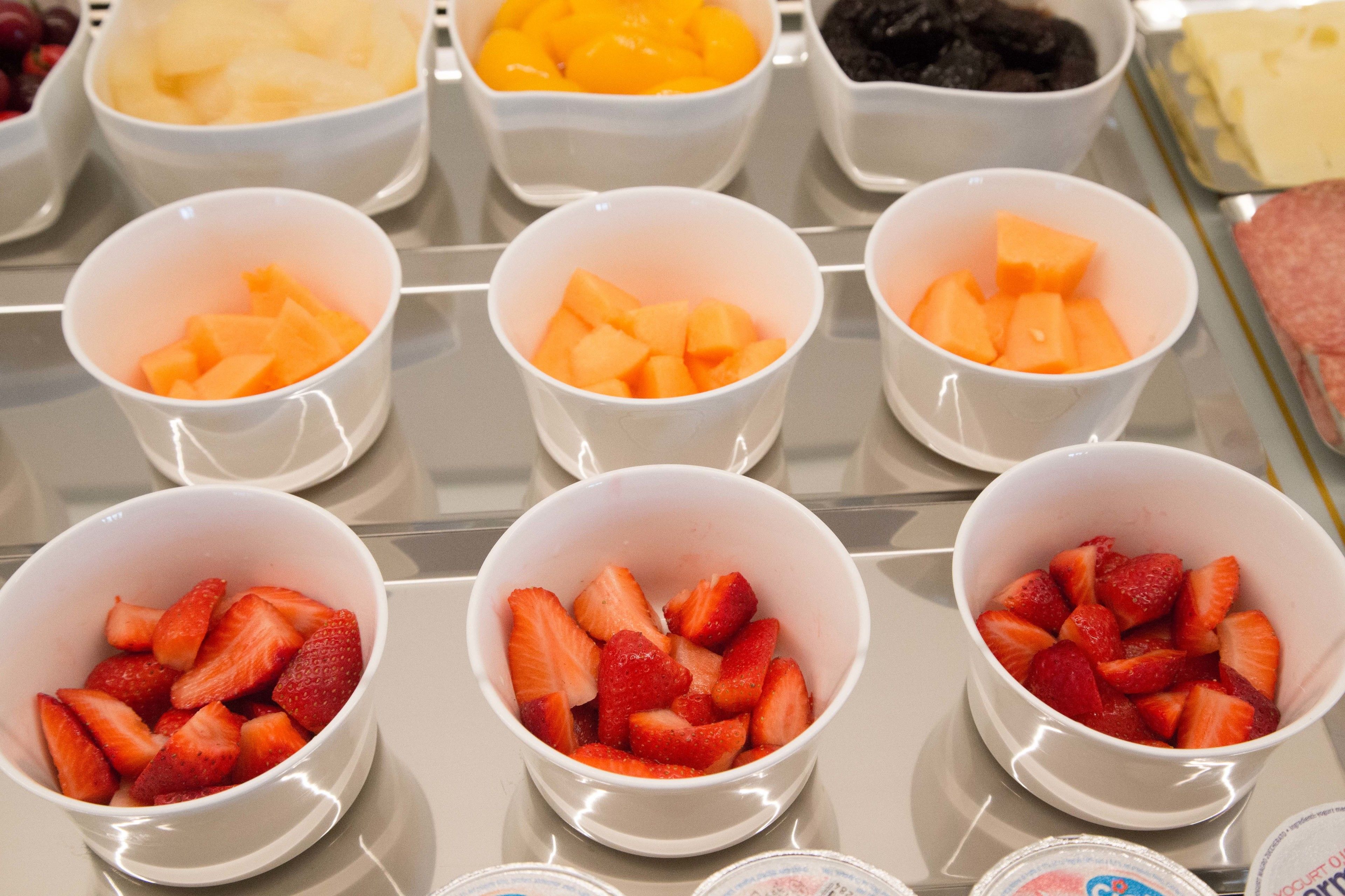 A selection of fruit bowls with various fruits including strawberries and cantaloupe.