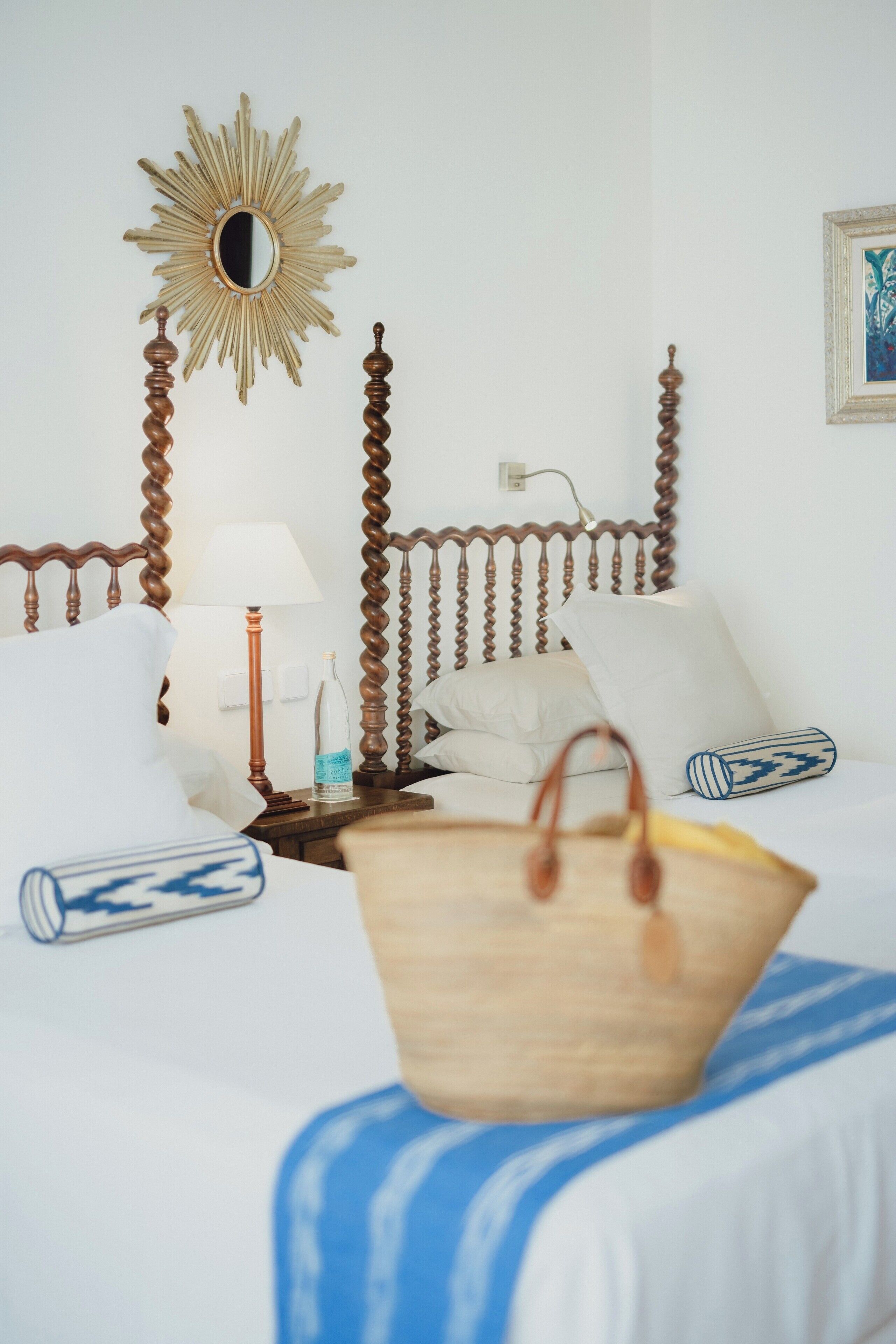 A neatly made bed with a wooden headboard, a bedside lamp, and a decorative mirror.