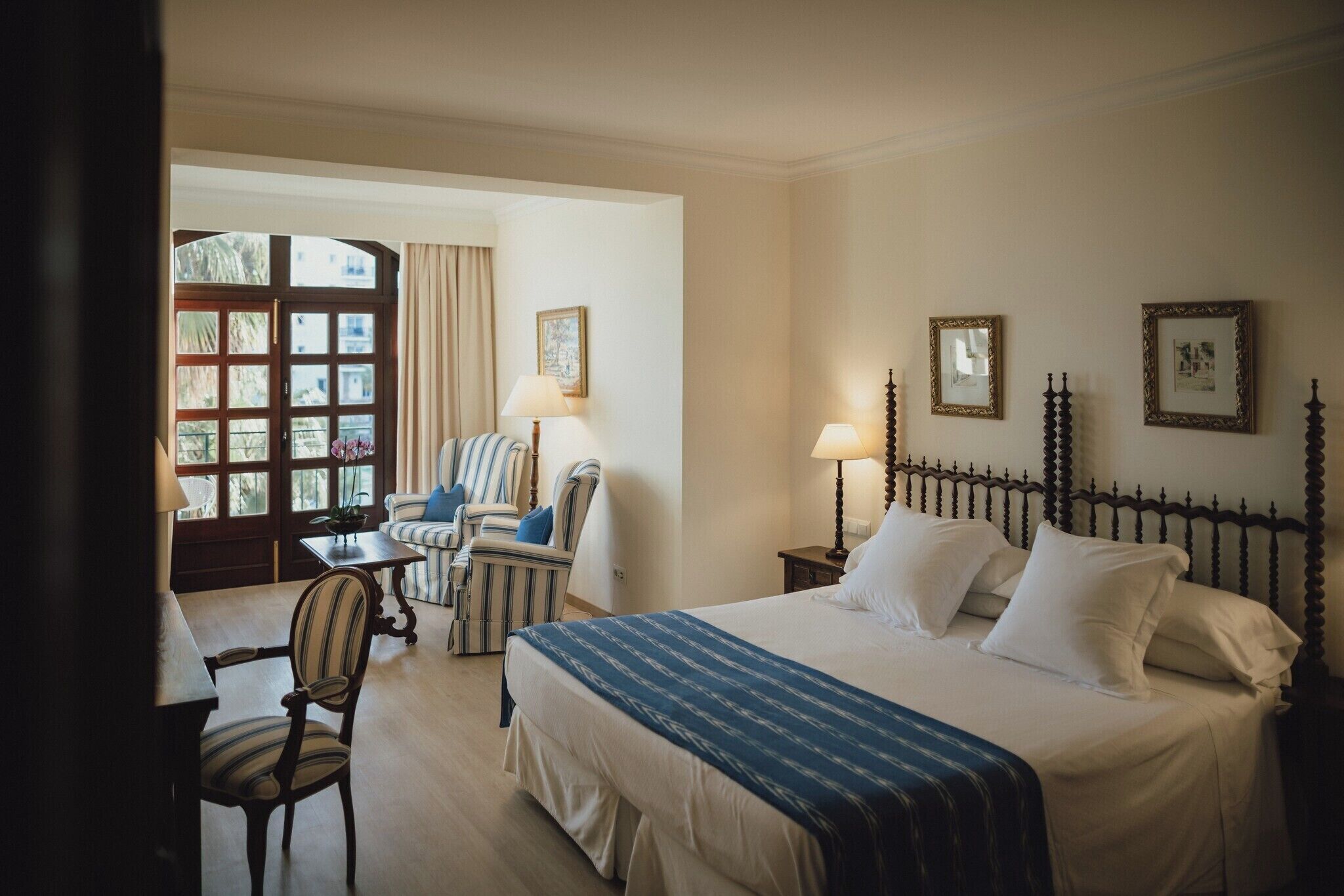 A hotel room with a bed, a chair, a table, and a window with curtains.