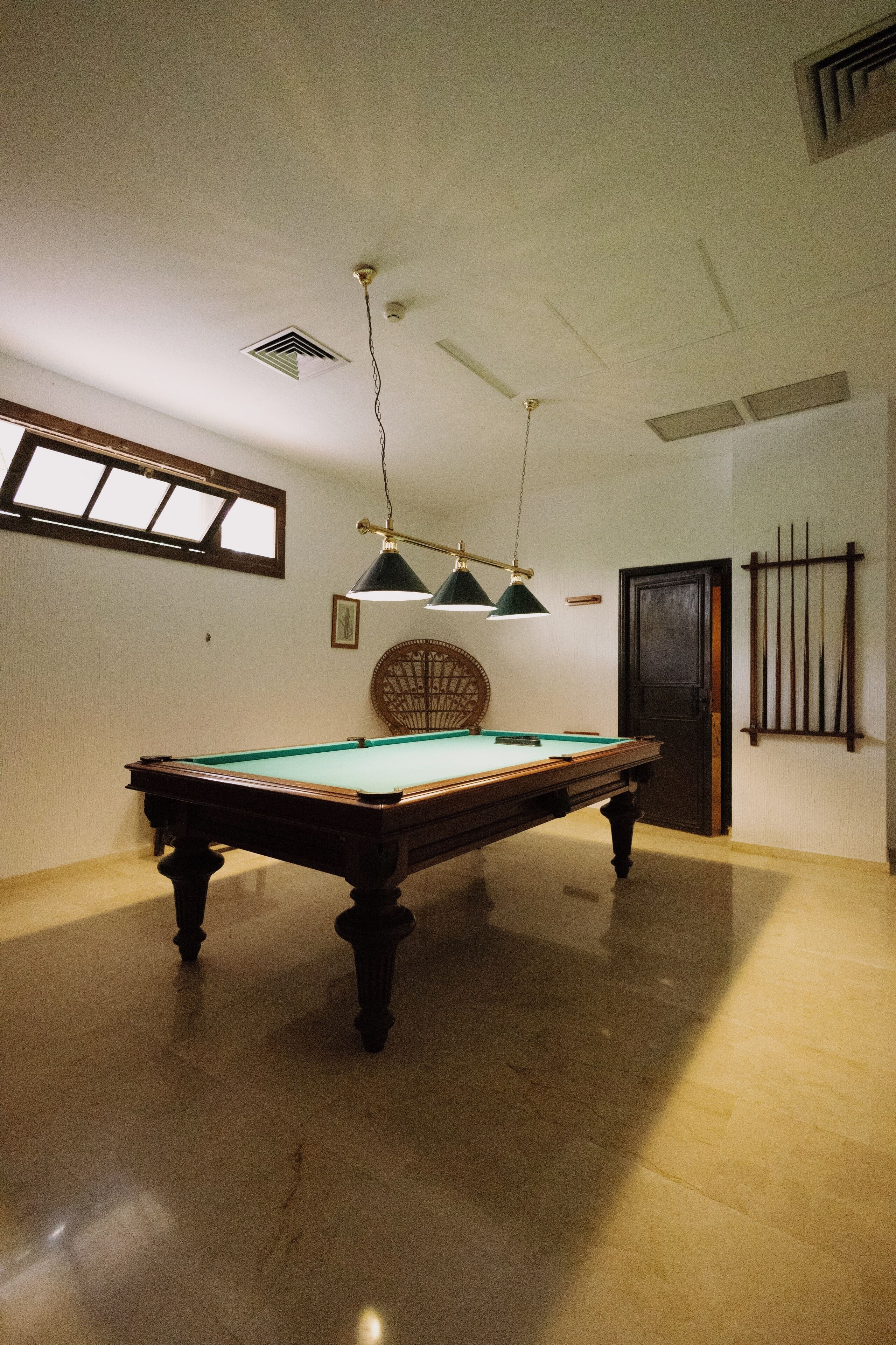 A pool table in a room with a ceiling fan, a window, and a door.