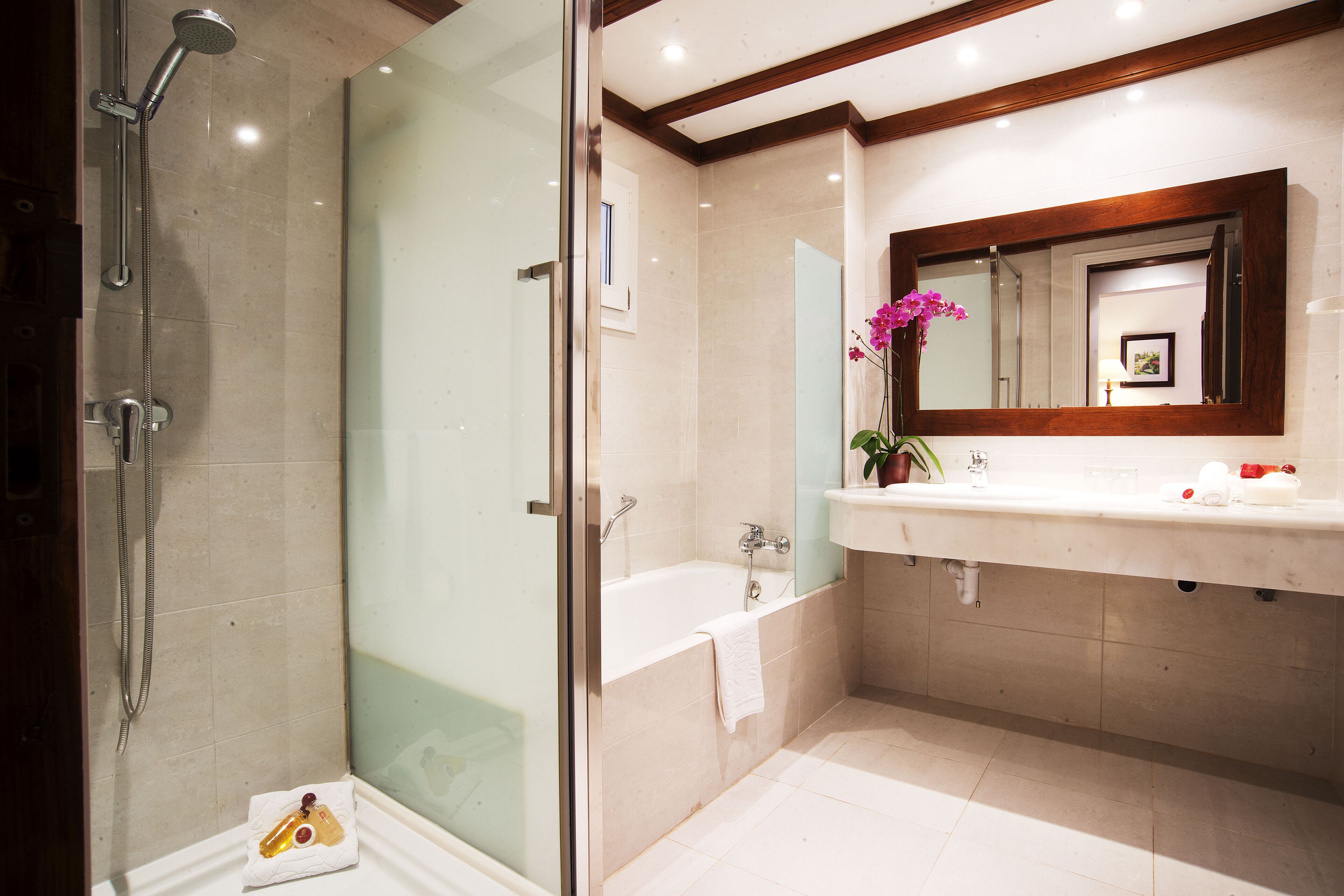 Un baño moderno con ducha envuelta en cristal, una bañera y un tocador con espejo.
