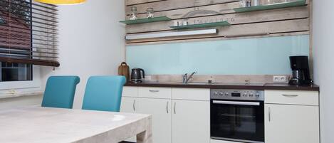 Una cocina con encimera de madera, un lavamanos, un horno y una mesa de comedor con sillas.