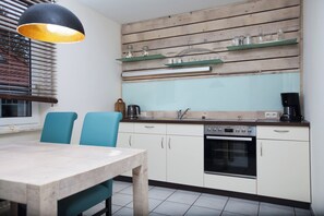 Una cocina con encimera de madera, un lavamanos, un horno y una mesa de comedor con sillas.