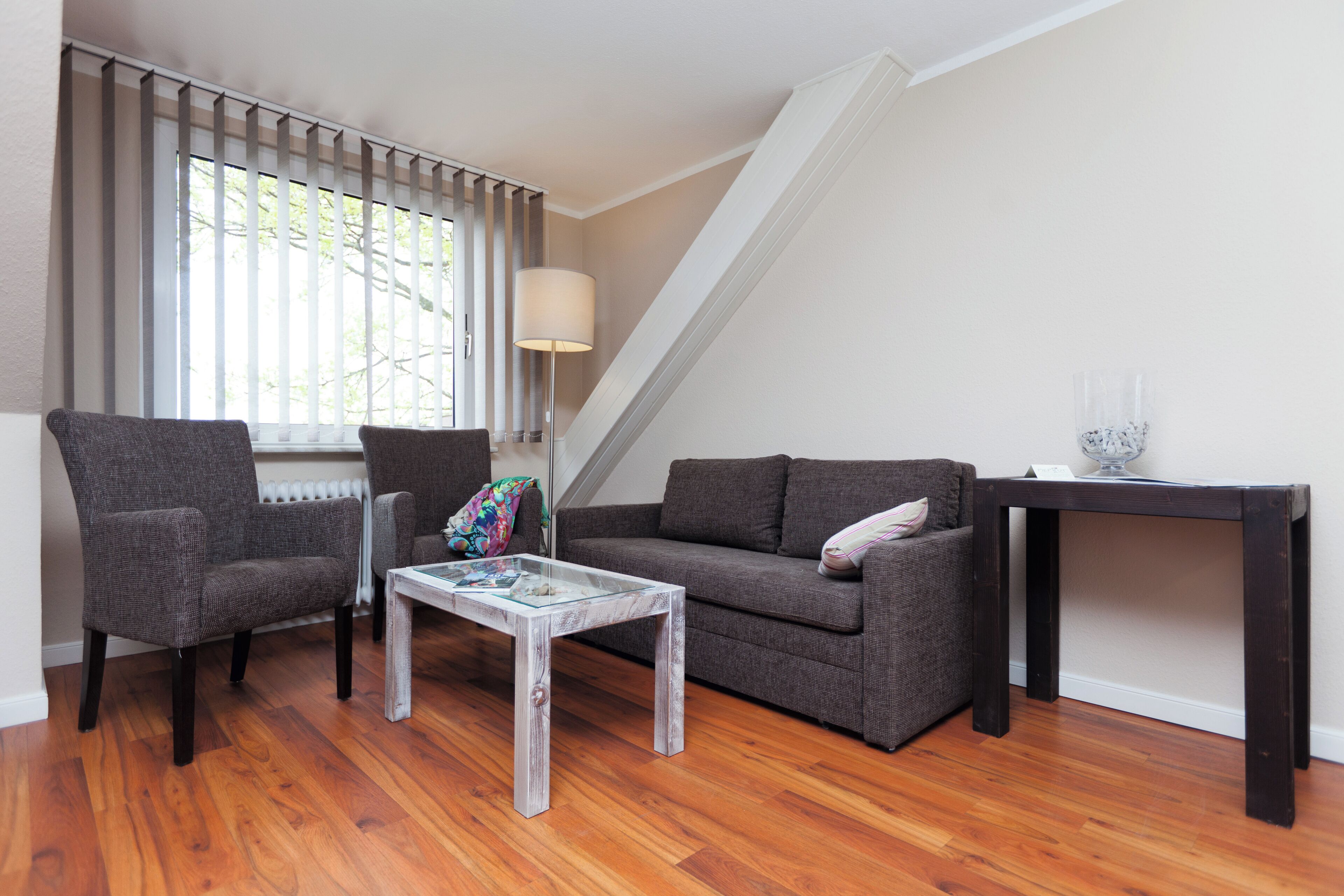 A living room with a sofa, two armchairs, a coffee table, a lamp, and a side table.