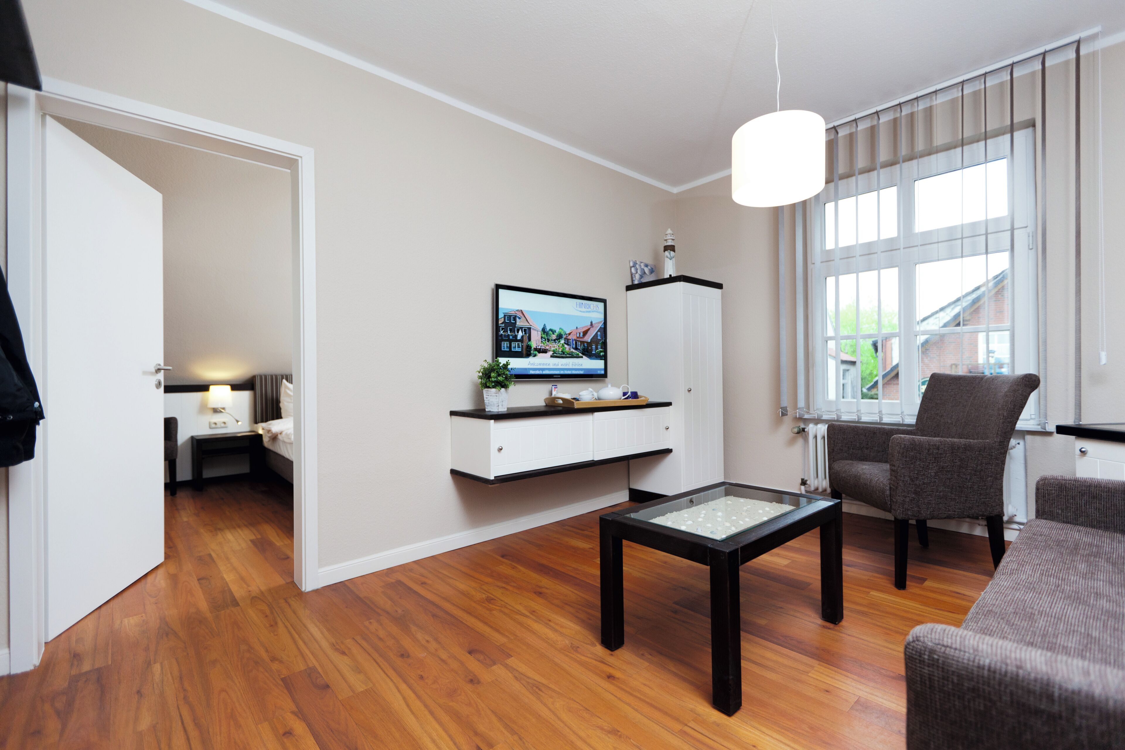A modern living room with a television, a glass-top coffee table, and two armchairs.