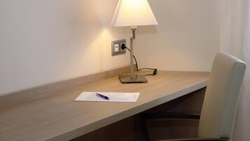 A desk with a lamp, a chair, and a notepad with a pen.