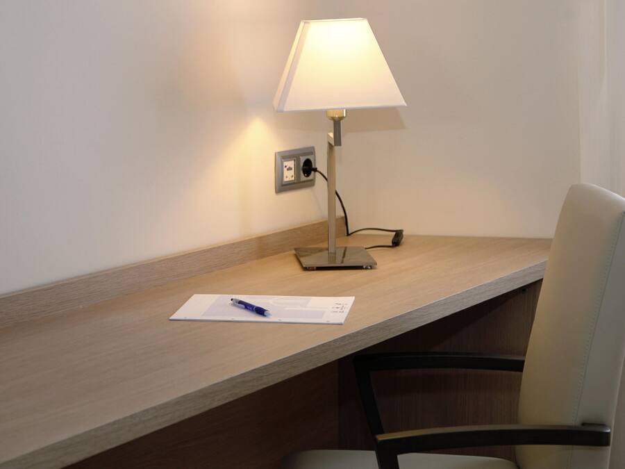 A desk with a lamp, a chair, and a notepad with a pen.