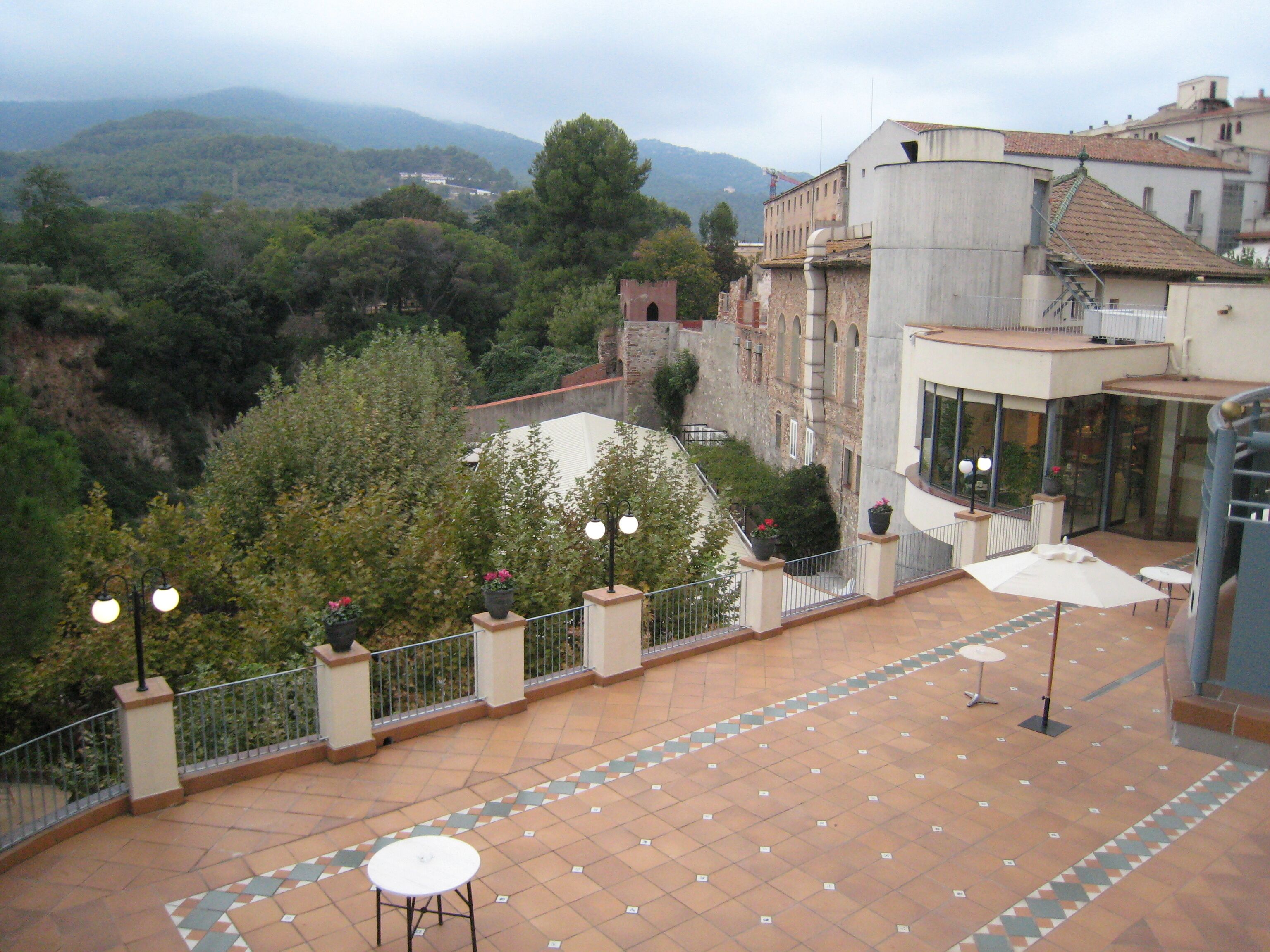 Una terraza con piso de baldosas, una mesa blanca y una barandilla.