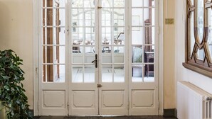 A grand arched doorway with glass panels, a chandelier, and a radiator. - Balneari Termes Victòria (Caldes de Montbui)