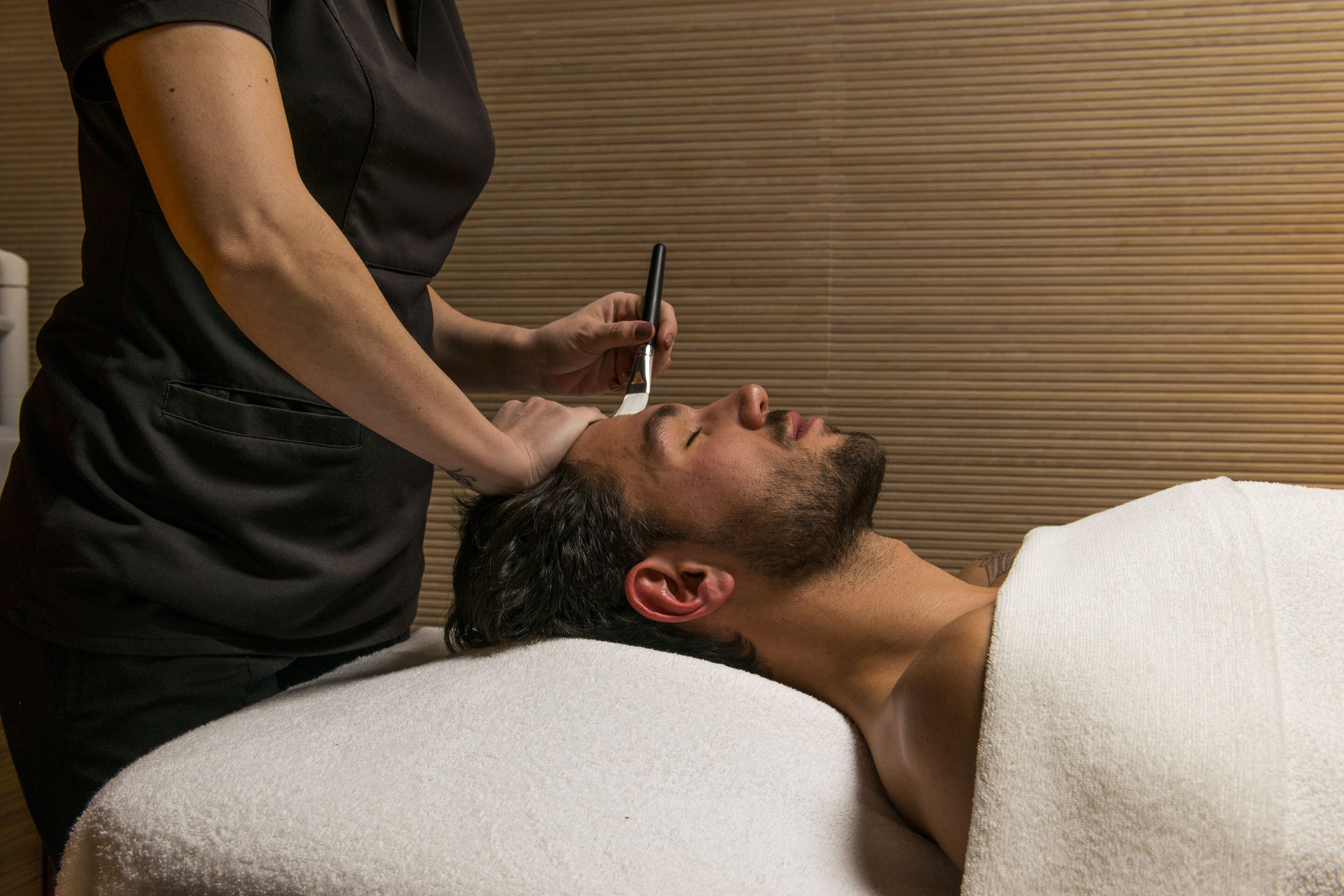 A person lying on a treatment bed receiving a facial treatment.