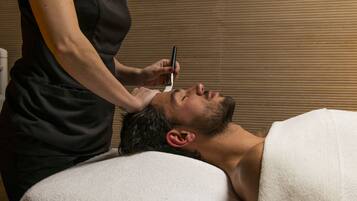 A person lying on a treatment bed receiving a facial treatment.
