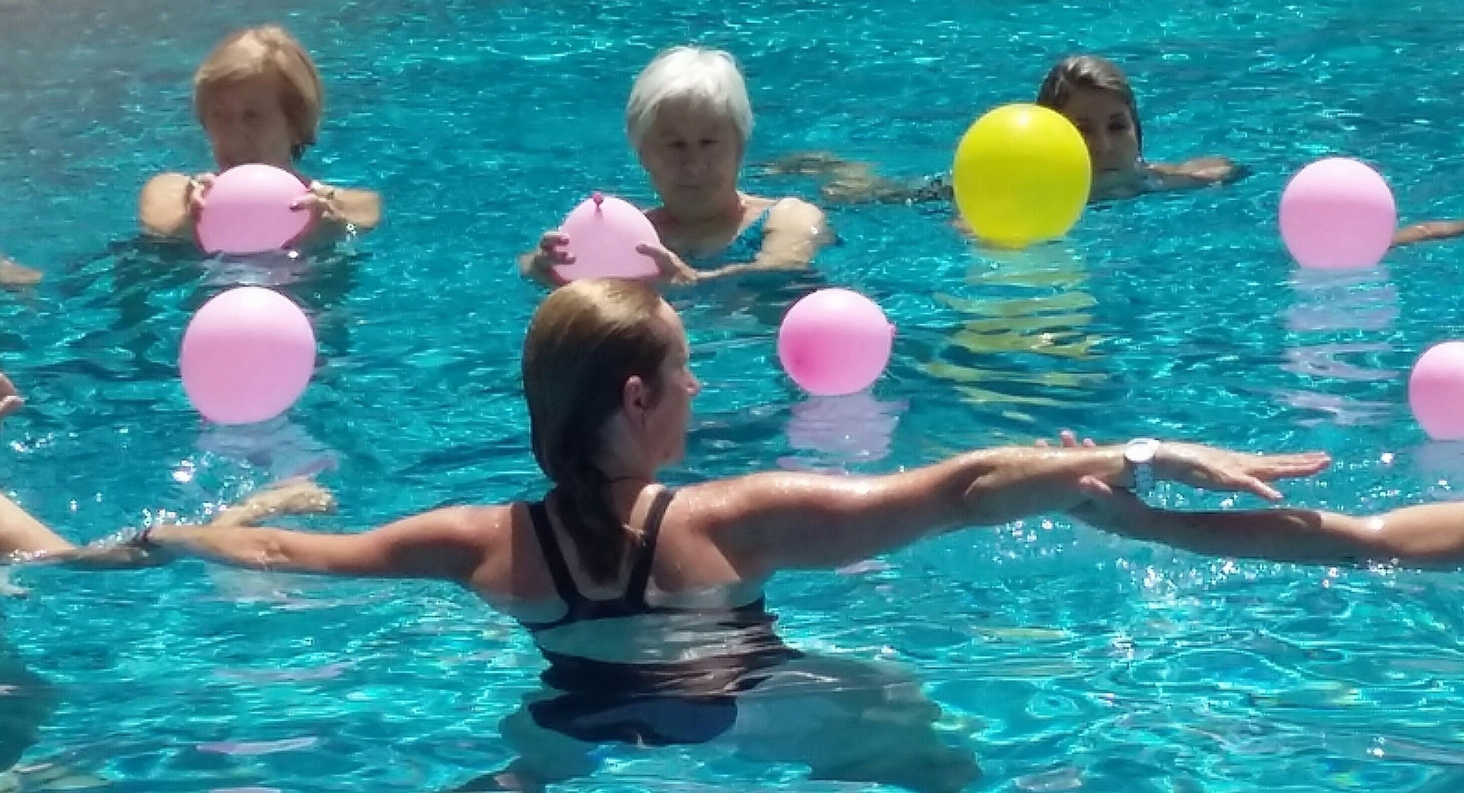 A swimming pool with clear blue water and several people swimming.