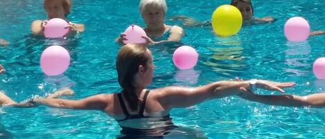 A swimming pool with clear blue water and several people swimming.