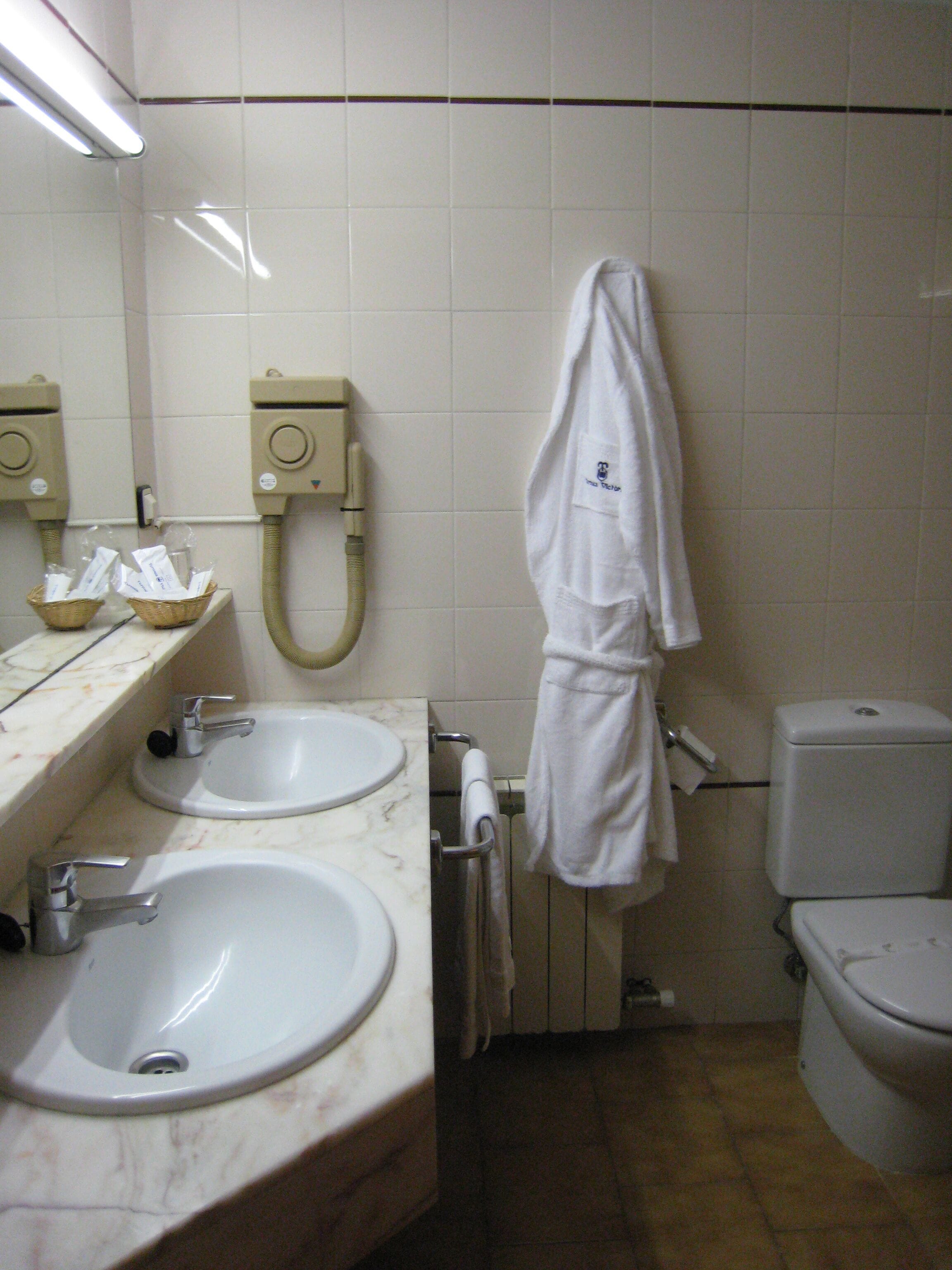 A bathroom with two sinks, a toilet, and a towel rack.