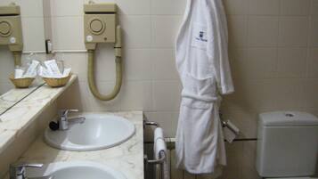 Een badkamer met twee wasbakken, een toilet en een handdoekhouder.