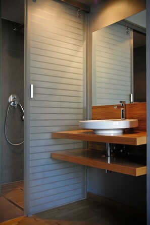 A modern bathroom with a wooden vanity, a large mirror, and a shower with a glass door. - La Gioia Modern Designed Studios (Kraków)