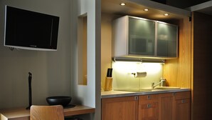 Une cuisine moderne avec des meubles en bois, un four à micro-ondes encastré et un téléviseur à écran plat fixé au mur.