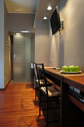 Un comedor con mesa de madera, sillas y un televisor fijado a la pared.