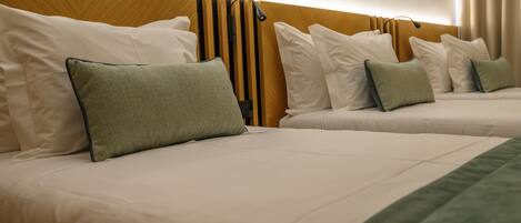 Une chambre d’hôtel avec deux lits, chacun étant équipé de draps blancs et d’oreillers verts.