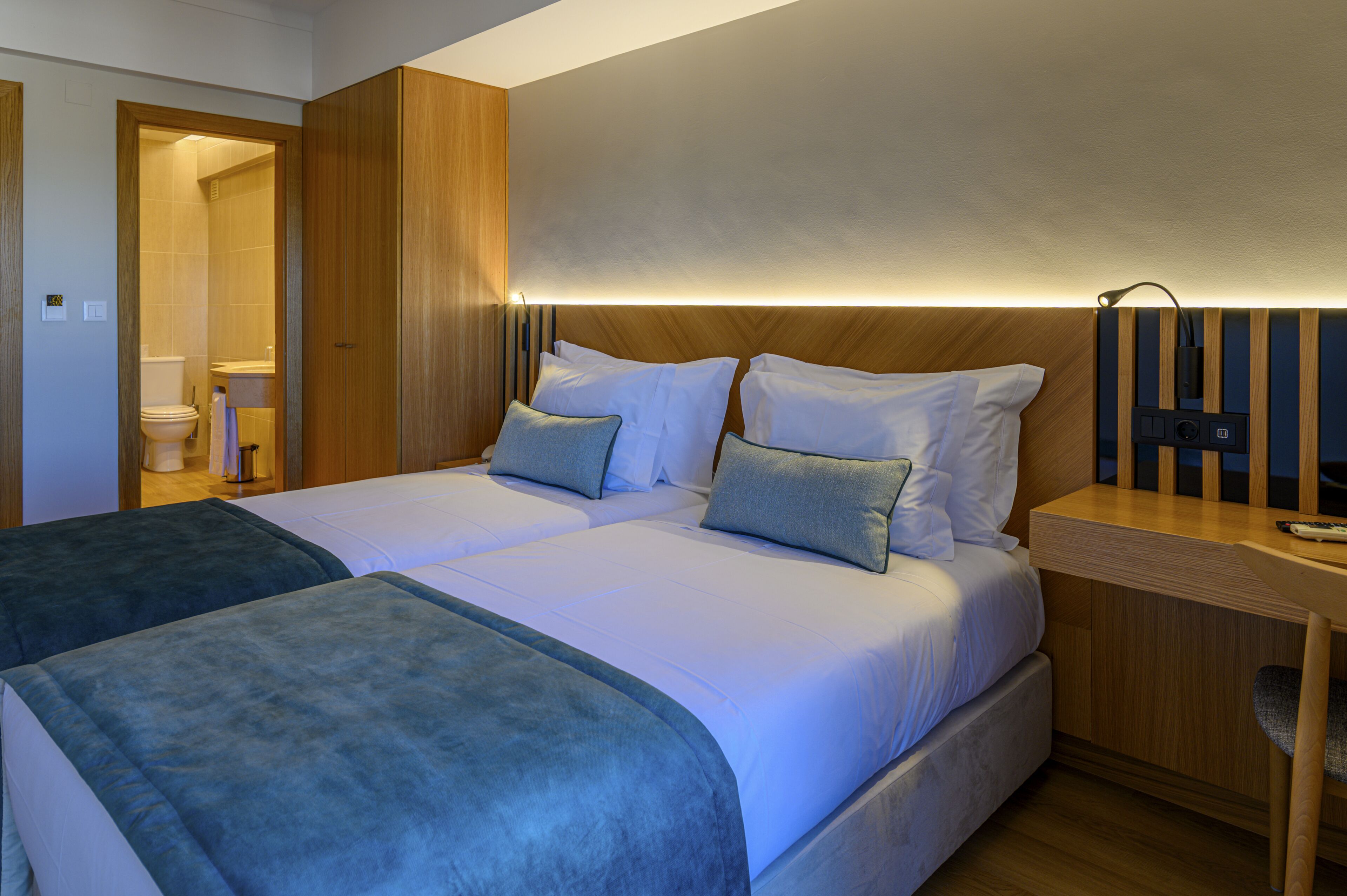 A double bed with two pillows, a bedside table, and a wooden headboard.