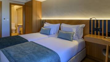 A double bed with two pillows, a bedside table, and a wooden headboard.