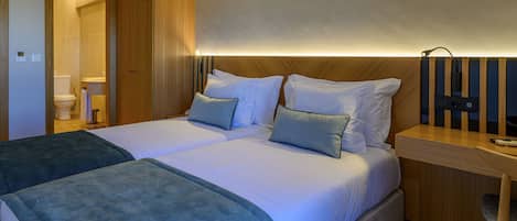 A double bed with two pillows, a bedside table, and a wooden headboard.