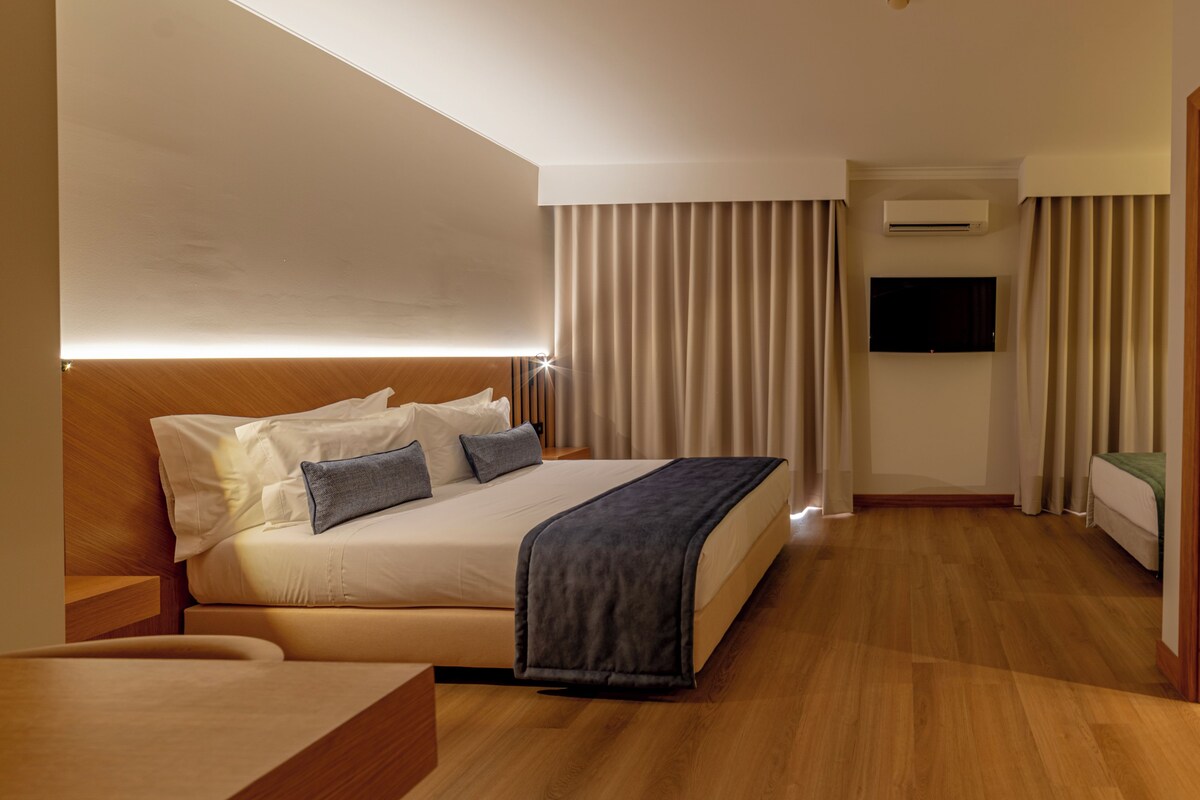 Una habitación de hotel con cama, mesita de noche, televisión y aire acondicionado.