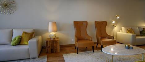 Una sala de estar moderna con un sofá, dos sillones, una mesa de centro y una lámpara.