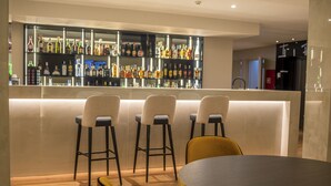 Una zona de bar con taburetes y una mesa redonda, una estantería repleta de licores y una decoración interior moderna.