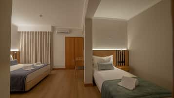 A hotel room with two beds, a desk, a chair, and a nightstand with a lamp.