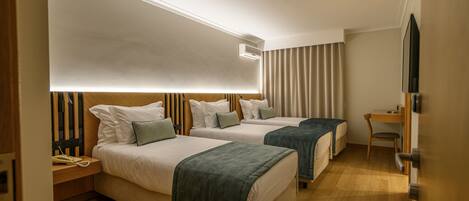 A hotel room with two beds, a desk, a chair, a TV, and a bedside table with a phone.