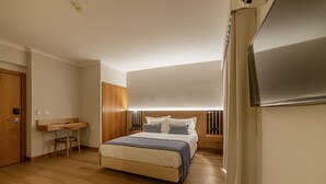 Una habitación de hotel moderna con una cama grande, un escritorio y un armario.