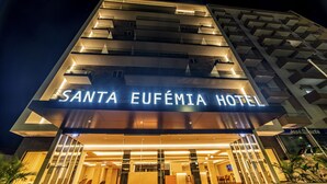 Fachada del Hotel Santa Eufemia con señalización iluminada, diseño arquitectónico moderno y entrada visible.