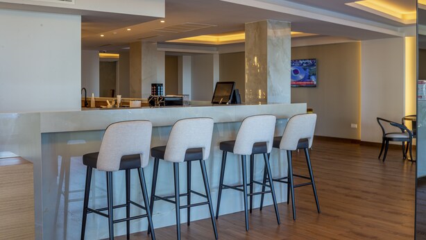 Zona de bar moderna con encimera de mármol y cuatro taburetes.