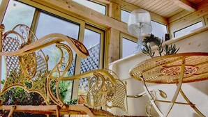 Un intérieur en bois avec de grandes fenêtres, une chaise en métal décorative et une table ronde.
