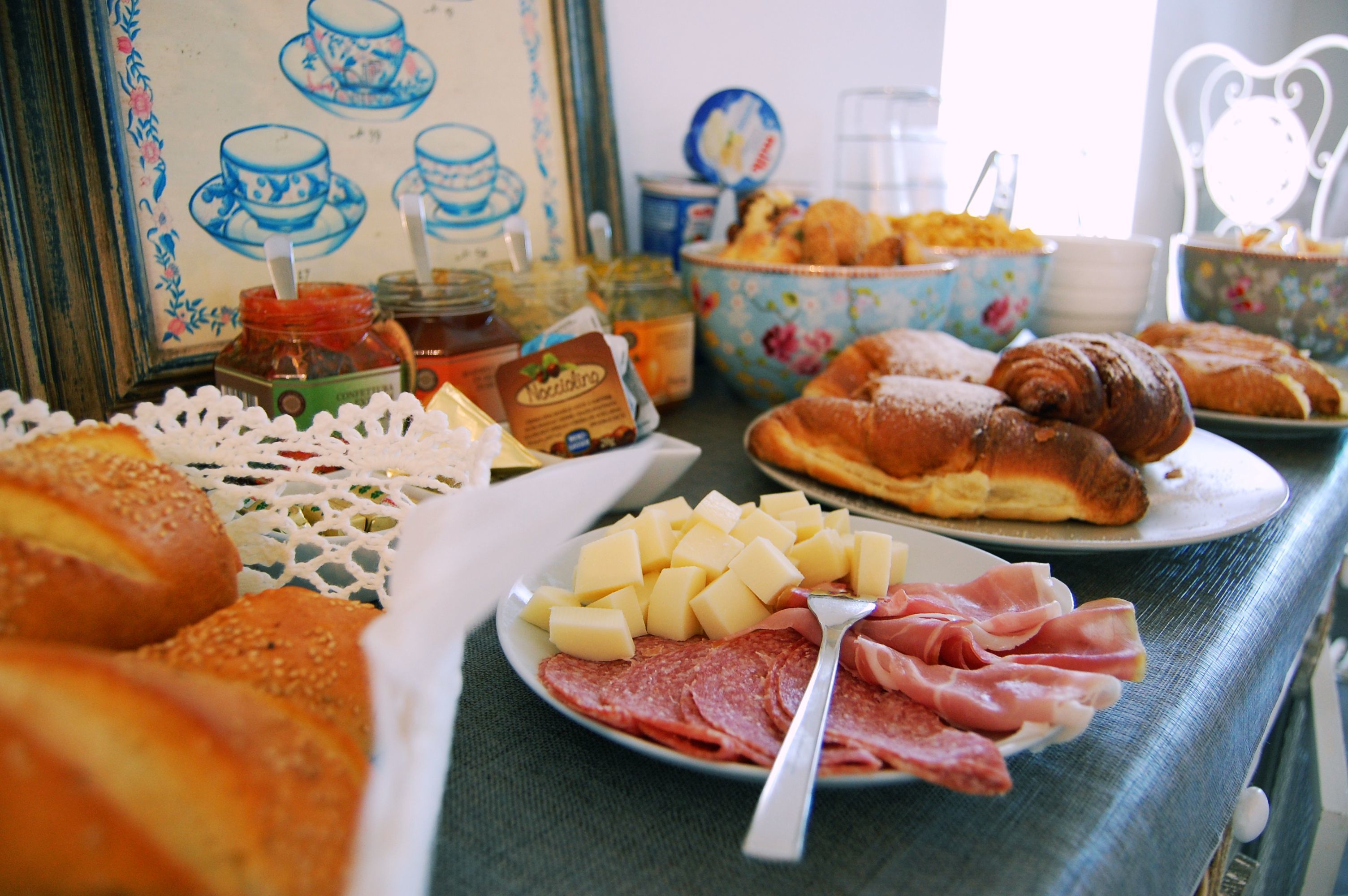 A breakfast buffet with various foods including pastries, cheese, and meats.
