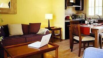Una sala de estar con sofá, mesa de centro y comedor con mesa y sillas.