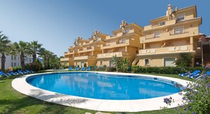 A hotel with a swimming pool surrounded by blue lounge chairs. - Apartamentos Vista Real (La Línea de la Concepción)
