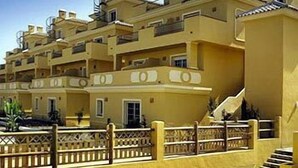 Um edifício residencial com vários andares, varandas, escadaria e portão.