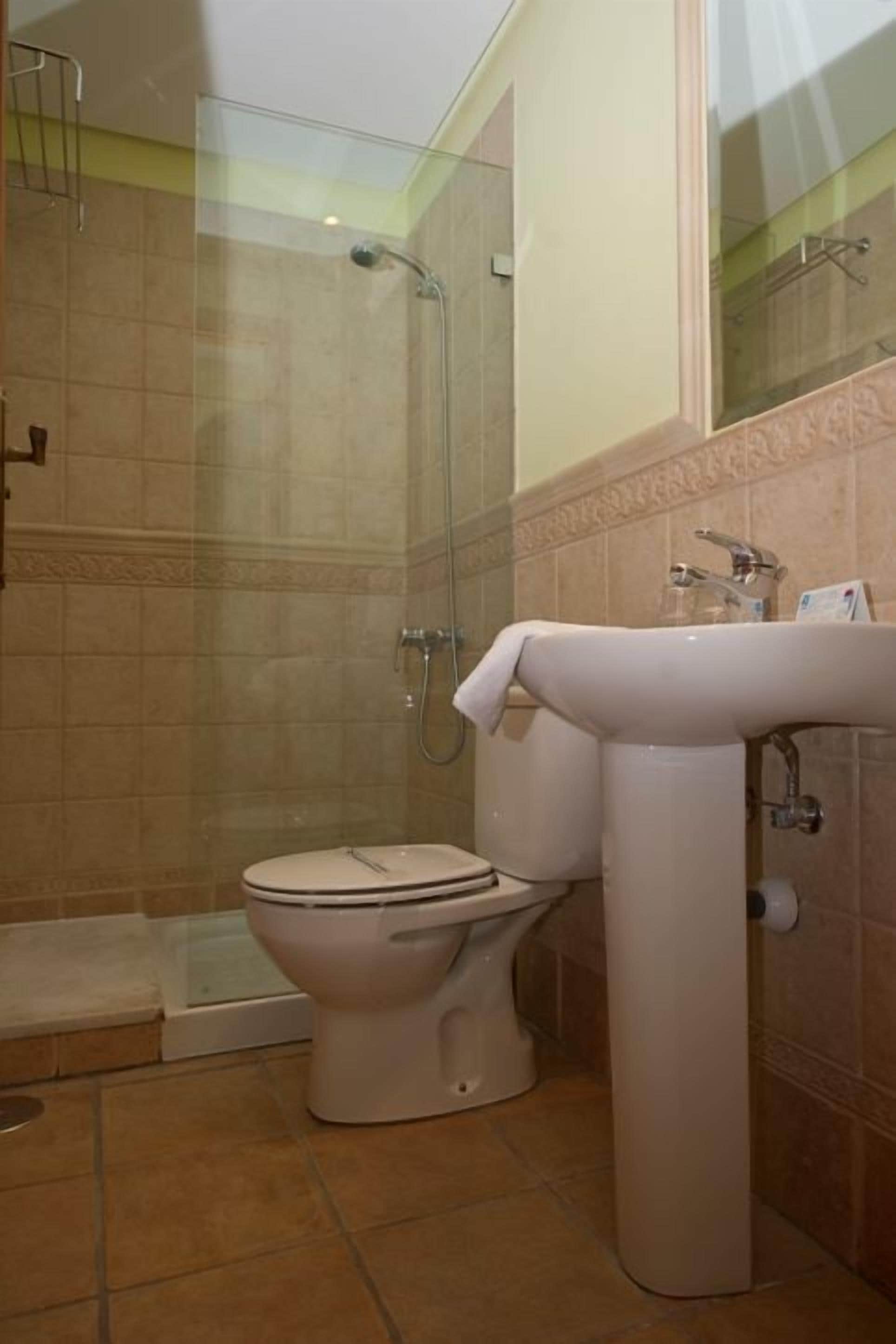 A bathroom with a glass-enclosed shower, a toilet, and a sink.